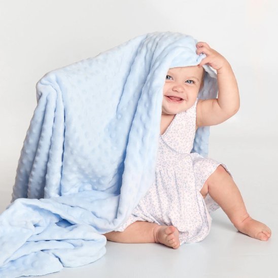 petite fille souriante avec sa Couverture bébé sur la tête